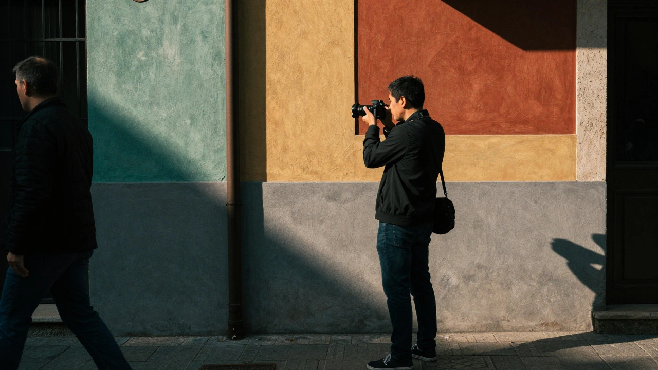 Photographer shooting from the hip in front of a colorful wall as a person walks by.