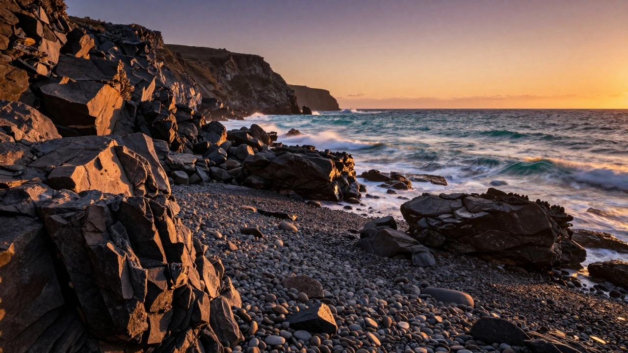 Rugged coastal rocks in the foreground acting as leading lines toward a sunset ocean.
