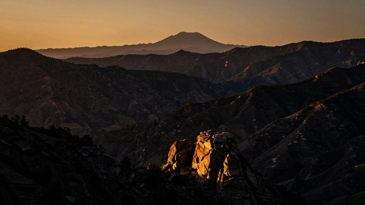 Desert mountain peak illuminated by sunset against deep dark shadows