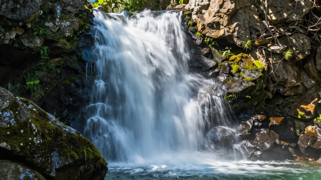 Silky waterfall flowing over rocks in bright sunlight, demonstrating long-exposure effects