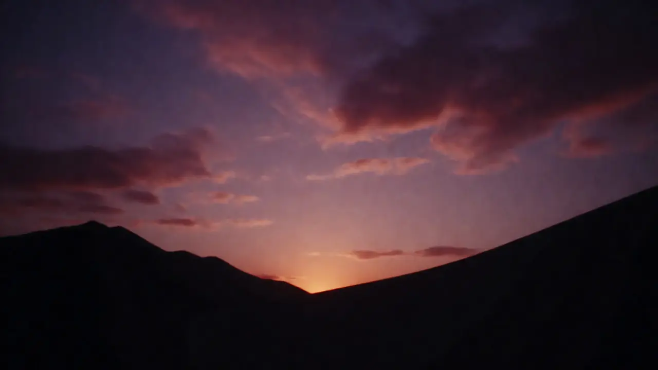 Silhouetted mountains against a purple and orange post-sunset twilight sky.