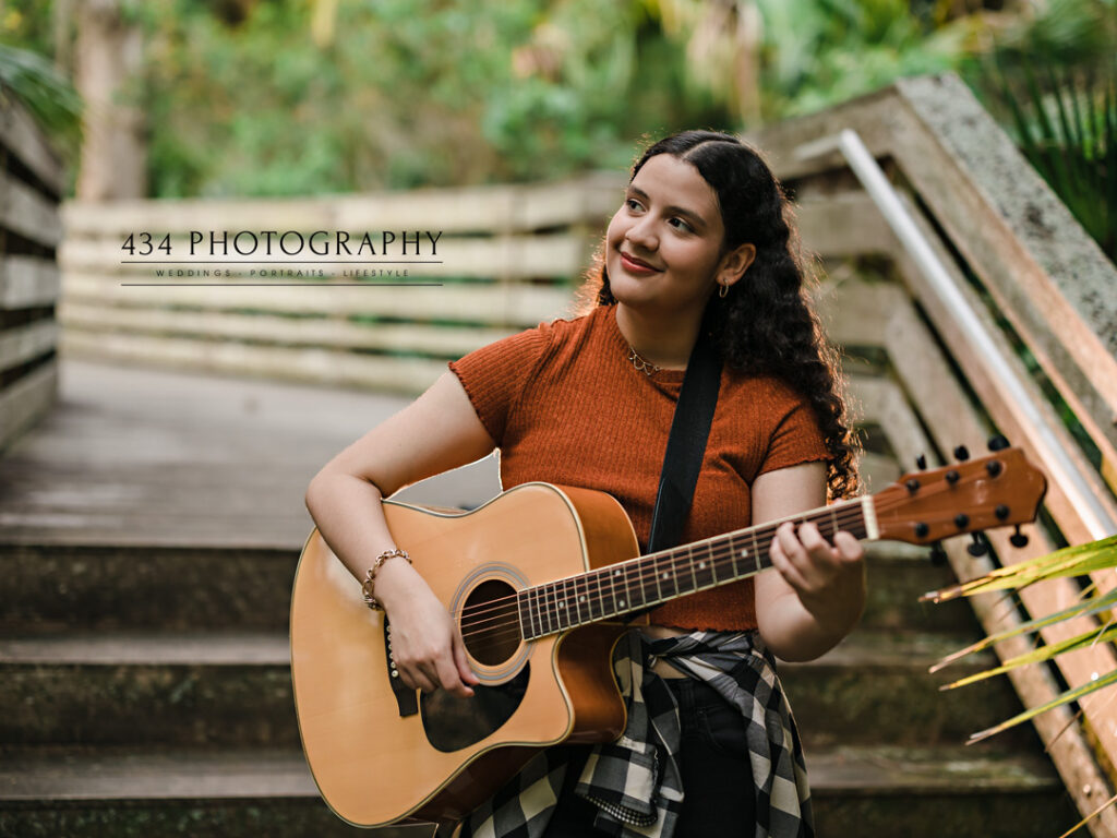 a senior being herself in front of the camera playing her guitar.