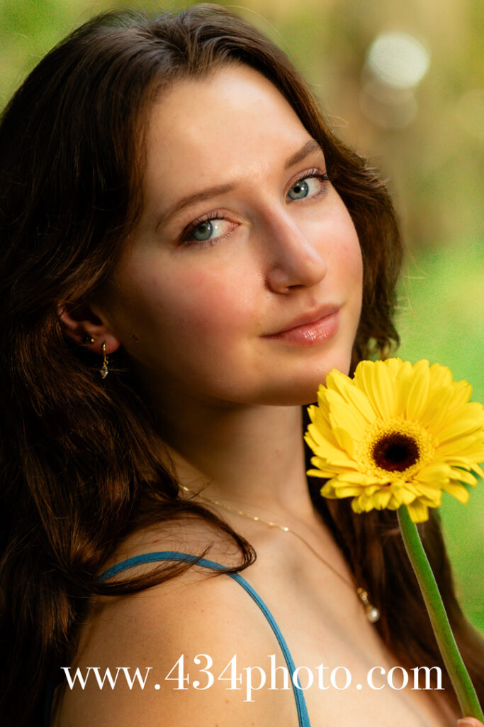 portrait of a high school senior holding a yellow flower